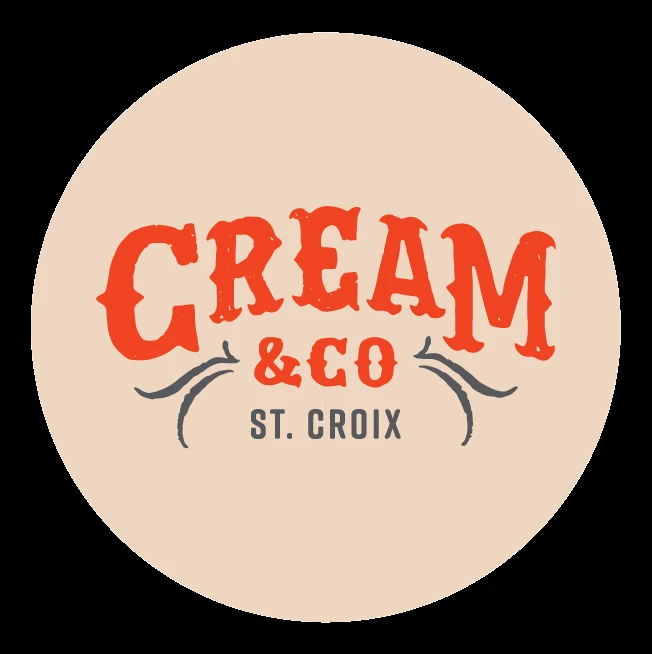 The image is a logo featuring the text "CREAM & CO ST. CROIX" in stylized red and gray fonts on a beige circular background. logo on footer section.