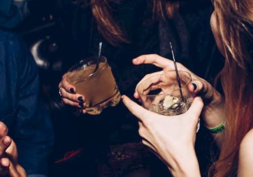 People enjoying drinks and conversation at a social gathering, holding cocktails and laughing.