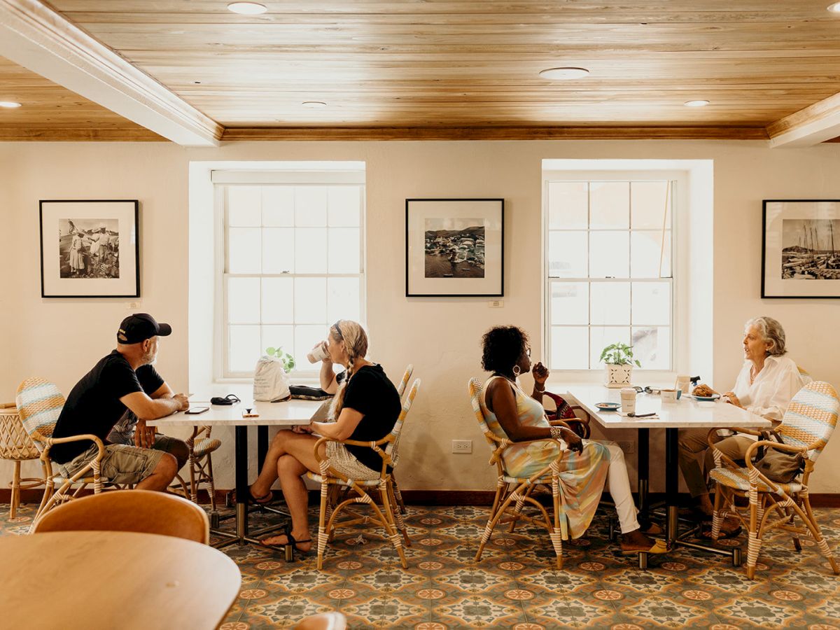 People sitting at tables in a cozy café with art on the walls and natural lighting from the windows.