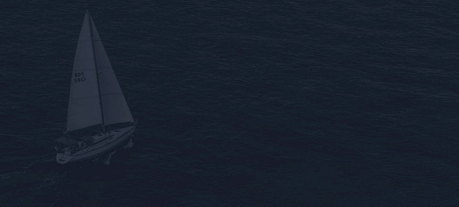A sailboat is navigating through dark, calm waters under a cloudy sky, with the sail marked by a number.