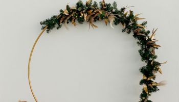 A decorative ring with foliage on one side, surrounded by wicker baskets, set against a light wall with string lights above.